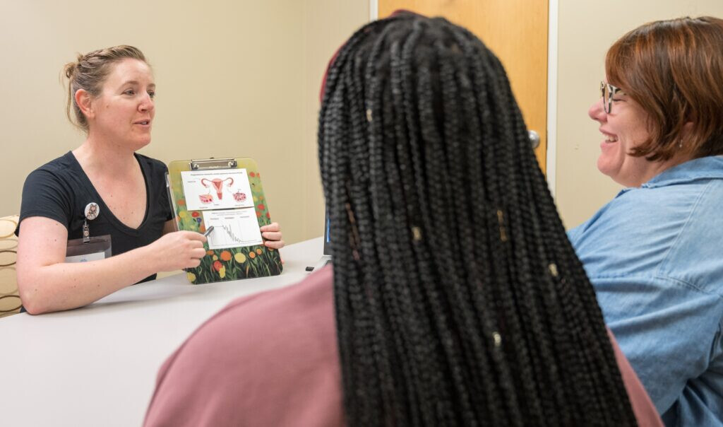 PMOS in Practice: Optimizing Health for People with PMOS &mdash; a clinician reviews an anatomy chart with two patients